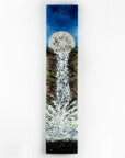 A fused glass wall panel featuring a rising full moon and a rushing waterfall. The design includes an organic colour-way and texture.