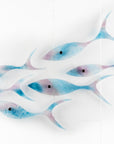 Fused glass shoal of fish in soft aqua and rose pink hues, creating an ocean inspired wall art installation.