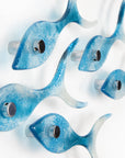 Side image of five fused glass fish, handmade in soft coastal blues, creating an ocean inspired wall art display.