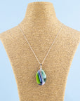 A fused glass pendant necklace, handmade in spring greens, soft pinks and marine blues, hung on a sterling silver chain.