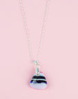 A fused glass pendant necklace, handmade in rose pinks, with dark blues hues, hung on a sterling silver chain.