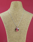 A sterling silver chain necklace with a round fused glass pendant featuring an autumnal, red design, handmade in vibrant colours and seen on a mannequin