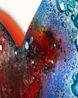 A detailed close up of this striking 95cm fused glass hear shaped wall panel handcrafted in Cornish studio in bright reds, aqua blues and lots of textured detailing.