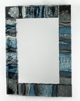 A fused glass oblong mirror, handmade using soft coastal blue tinted and grey glass with delicate texture and a wavy design.