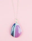 A fused glass pendant necklace handmade in rose pink hues, hung on a sterling silver chain.