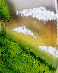 A close up of fluffy white clouds on a fused glass round panel featuring a design of the "Nearly Home Trees" located on a hill over-looking the A30.