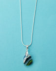 A sterling silver chain necklace with a teardrop-shaped fused glass pendant handmade featuring a ocean blues and sea greens in a marbled design