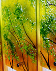 Close up of fused glass quintych featuring an abstract design of a woodland, with a vibrant sunset sky and textured detailing.
