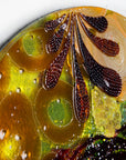 A fused glass round panel featuring organic autumn inspired patterns and shapes, in a vibrant yellow colour-way, handmade and inspired by the autumnal season.
