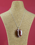 A sterling silver chain necklace with a fused glass pendant featuring a marbled pattern of reds and autumnal hues, seen on a mannequin.