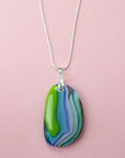 A sterling silver chain necklace with a fused glass pendant featuring a marbled swirl pattern of green, blue, and blushed white.
