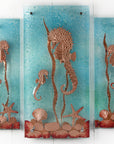 Fused glass staggered triptych, with hand-etched copper seahorses and ocean flora and an ocean blue background.