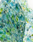 Close up of fused glass large vase, handmade from recycled glass in ocean green and blue hues.