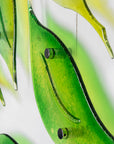 Close up of fused glass wall art display featuring individual spring leaves in vibrant colours.