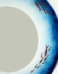 Close up of fused glass round mirror made in coastal blues and copper fish.