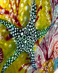 Details of hand-painted starfish in bright greens on a fused glass round wall panel.