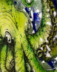 Details of a hand-painted green octopus with intricate detailing on a fused glass round panel.