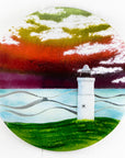 Fused glass round panel with a lighthouse deign and a vibrant coastal colour-way.