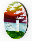 Fused glass round panel with a lighthouse design and sunset sky.