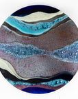 Abstract fused glass round panel, with wavy design in ocean purple colours and texture.