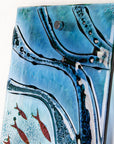 Close up of fused glass wall panel, with wavy detail and marine hues.