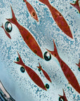 Copper fish detailing on a fused glass wall panel with blue colours.