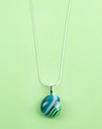 Close up of Fused glass pendant necklace, handmade with spring greens and hung on a sterling silver chain.
