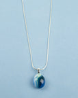 Close up of fused glass pendant necklace, handmade in marine blues, hung on sterling silver chain.