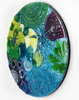 Side on image of round wall panel made from fused glass, inspired by the ocean reefs with starfish detailing and coastal colours.
