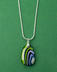 An artisan fused glass pendant necklace in coastal blues and greens, handcrafted in our studio. Finished with a sterling silver chain and fittings, a striking piece of wearable art.
