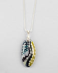 A fused glass pendant necklace on a sterling silver chain, handmade with soft coastal colours, with hand-painted dots and swirls.