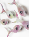 Close up image of a small fused glass shoal of fish, handmade in soft pinks and pearly whites.