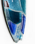 A close up of a fused glass surf board wall panel with mirror glass and mosaic inspired design. Handmade in marine blues, creating a lovely coastal piece of art work.