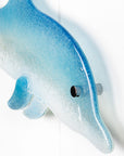 A close up of a fused glass sculptural dolphin wall panel, handmade in soft and coastal aqua blue and white.