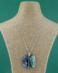 Fused glass pendant necklace, handmade in spring greens, with botanical hand-painted design. Hung on a sterling silver chain.