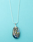 Fused glass pendant necklace handmade in rich coastal and sunset hues, including hand-painted patterns and hung on a sterling silver chain.