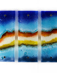 Three fused glass panels, forming a handmade triptych wall art piece, designed in coastal bright colours.