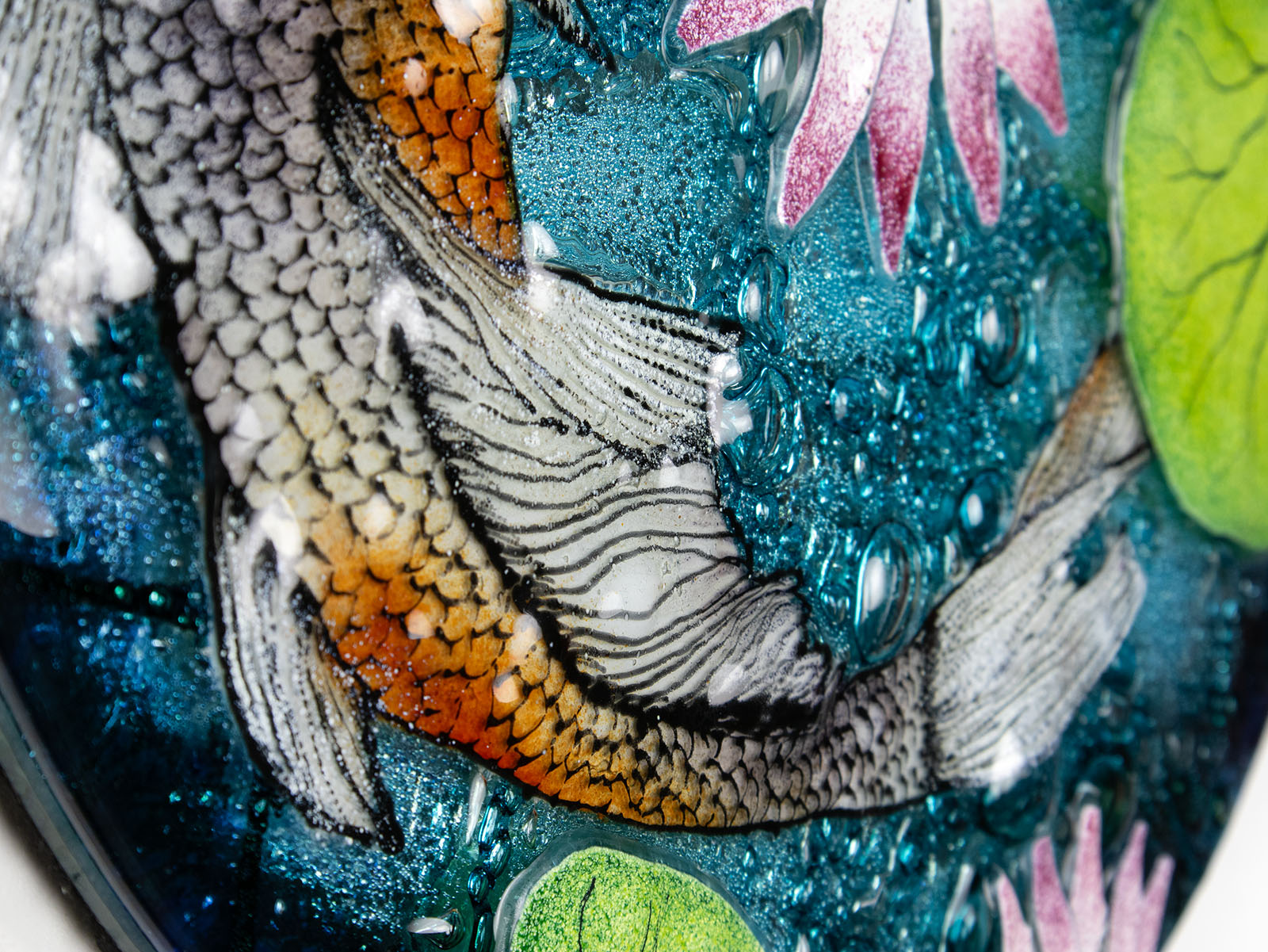 Painted details on a fused glass round panel featuring hand-painted koi carp design with waterlilies and marine blue background. 