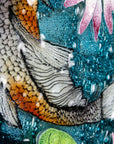 Painted details on a fused glass round panel featuring hand-painted koi carp design with waterlilies and marine blue background. 