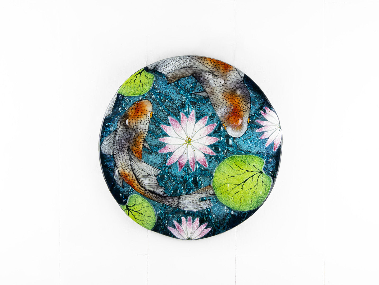A fused glass round panel featuring hand-painted koi carp design with waterlilies and marine blue background. 