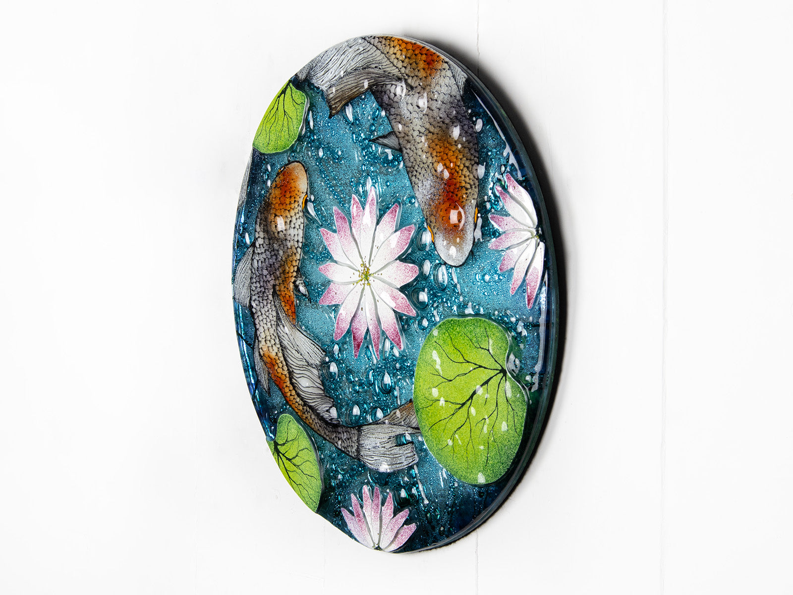 A fused glass round panel featuring hand-painted koi carp design with waterlilies and marine blue background. 