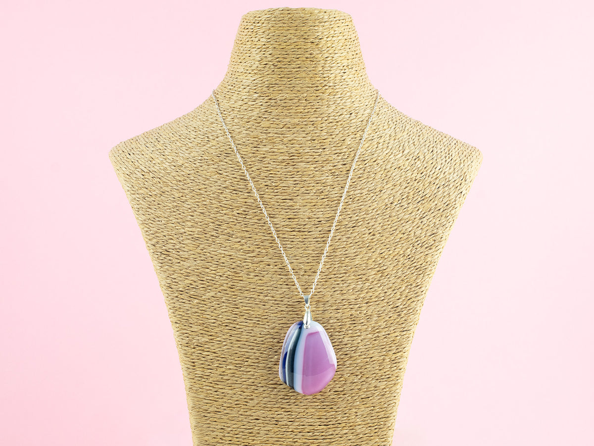 A fused glass pendant necklace handmade in rose pink hues, hung on a sterling silver chain. 