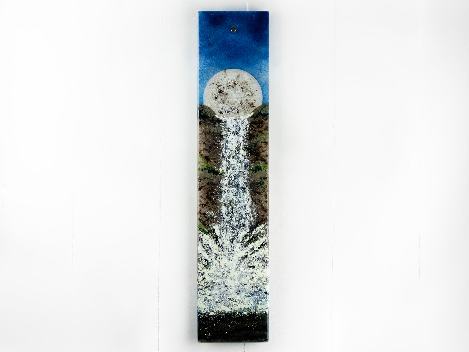 A fused glass wall panel featuring a rising full moon and a rushing waterfall. The design includes an organic colour-way and texture. 