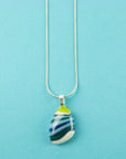 A teardrop-shaped fused glass pendant necklace with a marbled pattern of green, blue, and light teal, suspended on a sterling silver chain.