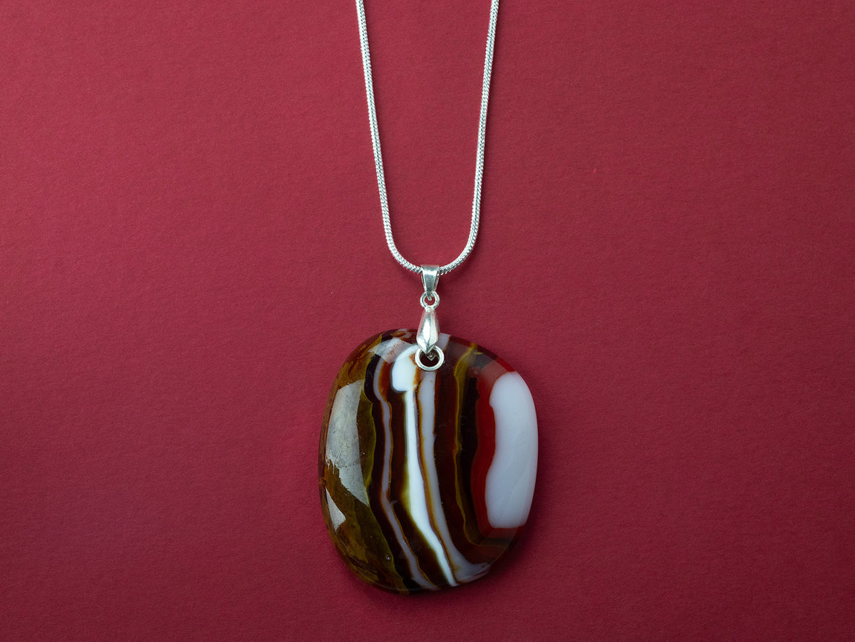 A sterling silver chain necklace with a fused glass pendant featuring a marbled pattern of reds and autumnal hues.