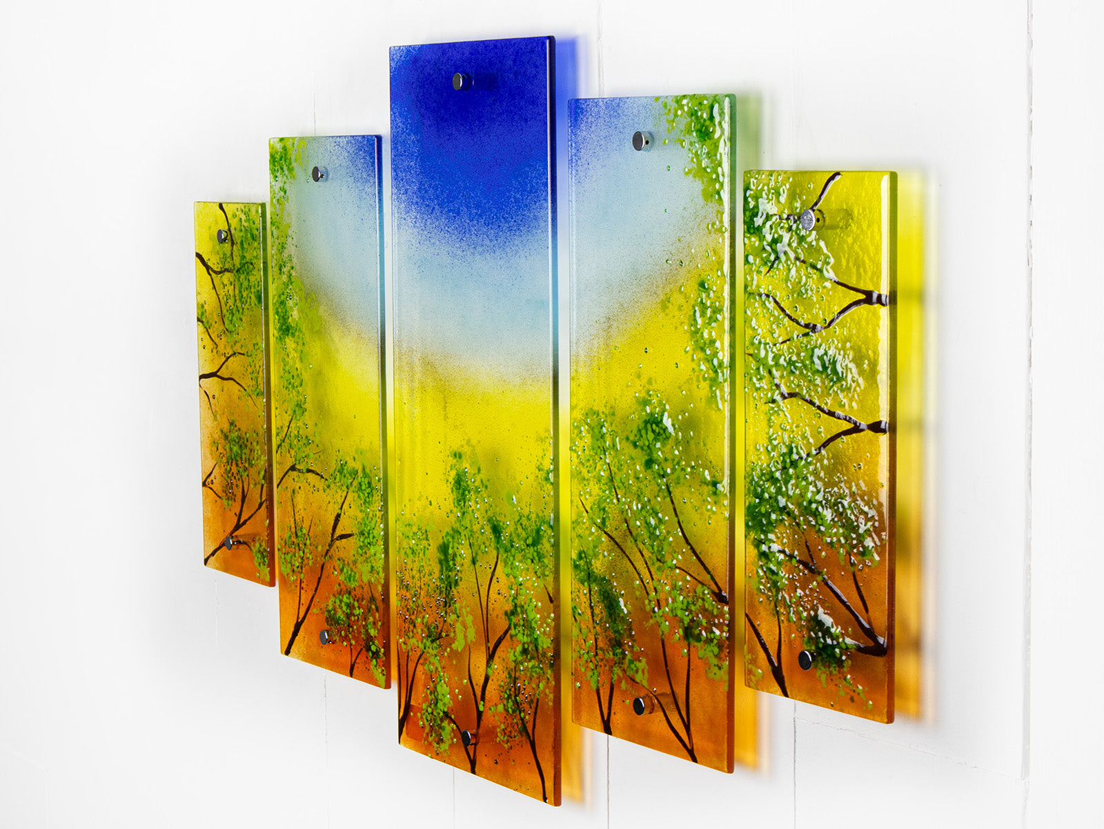 Fused glass quintych featuring an abstract design of a woodland, with a vibrant sunset sky and textured detailing. 