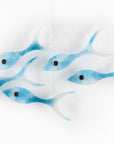 Five fused glass fish, handmade in soft coastal blues, creating an ocean inspired wall art display.