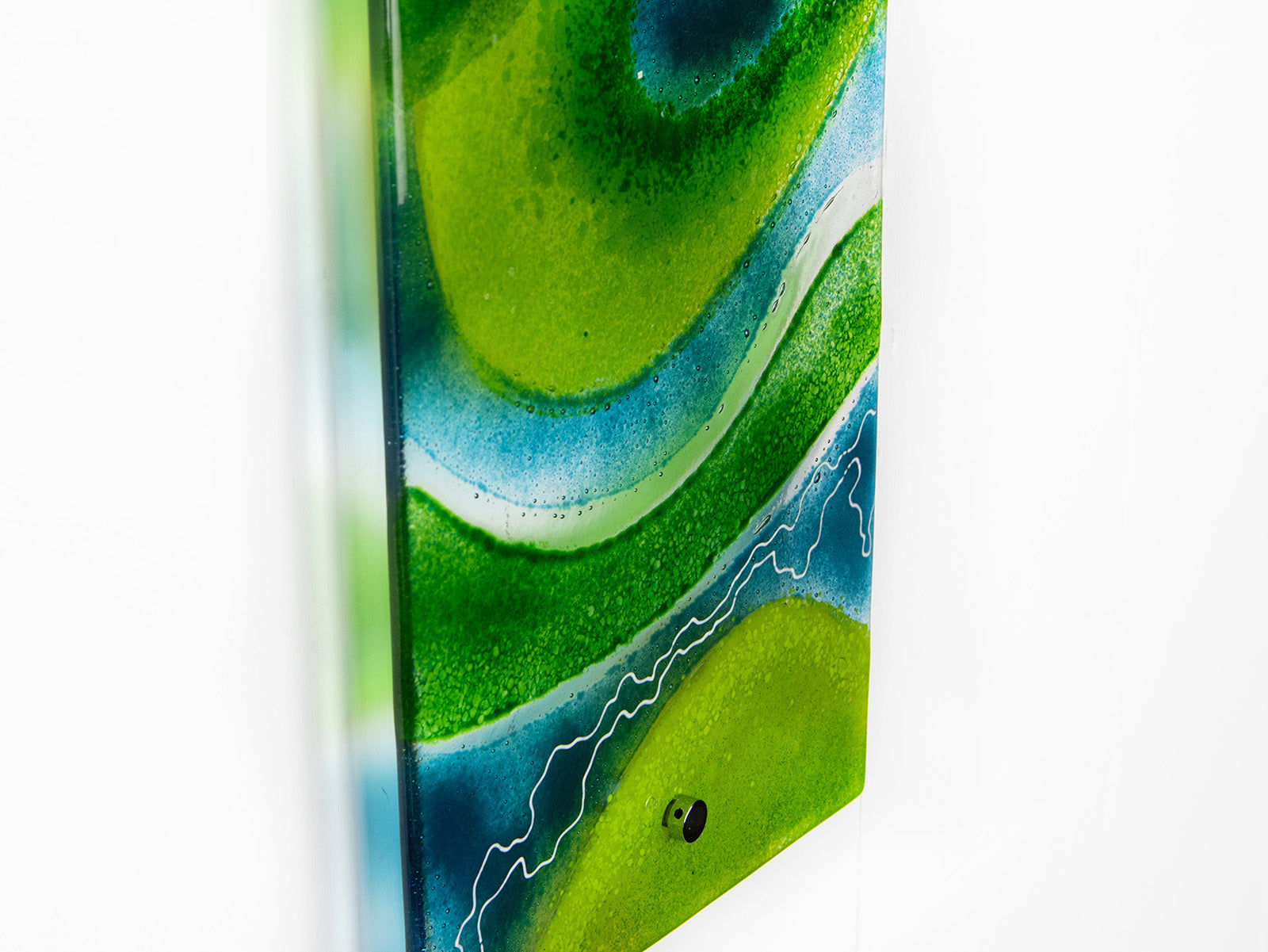 A close up of a fused glass wall panel in vibrant marine colours, in an abstract design. Hand-made in our Cornish studio. 