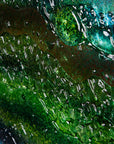 Details of a round textured glass wall art piece featuring an abstract design with wavy organic hues.