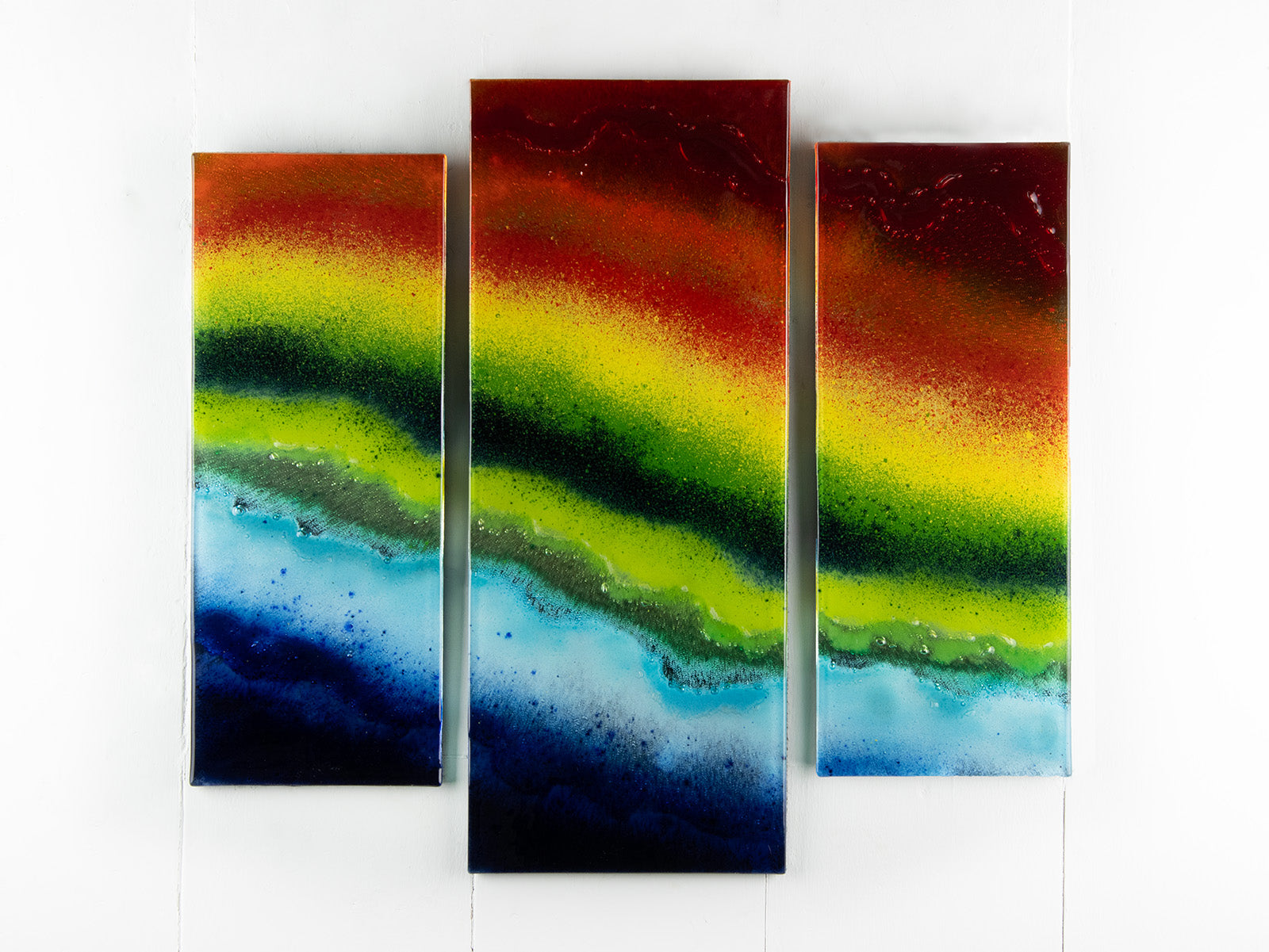 Fused glass staggered triptych in bright rainbow colours, placed onto mirror glass. A vibrant piece of wall art. 